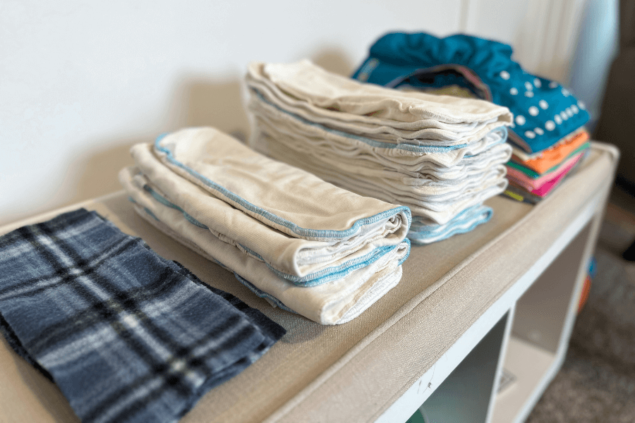 stacks of cloth diaper supplies on a bench - cloth diapering tips