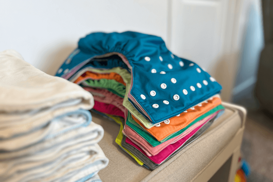 stack of cloth diapers on a changing pad - cloth diapering tips