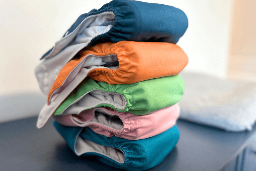 stack of cloth diapers on a blue changing table - cloth diapering tips