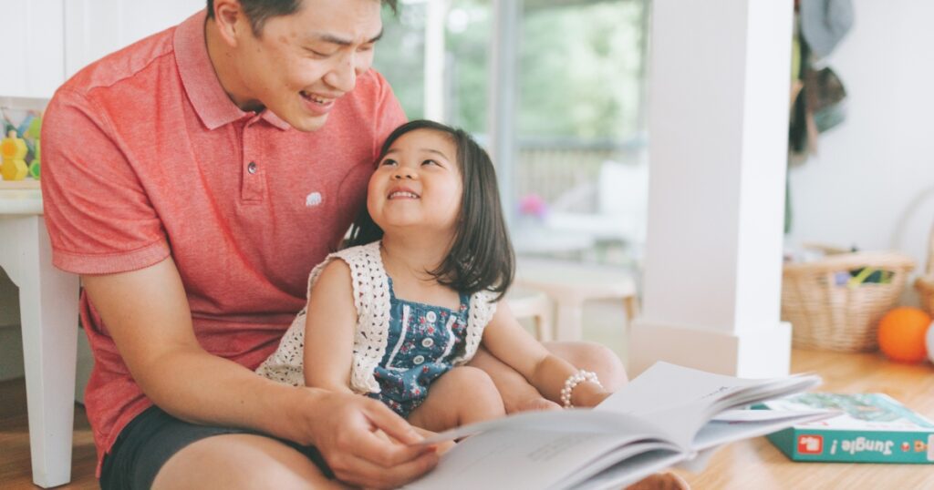 toddler fathers day gifts. picture of a dad and a daughter reading a book together.