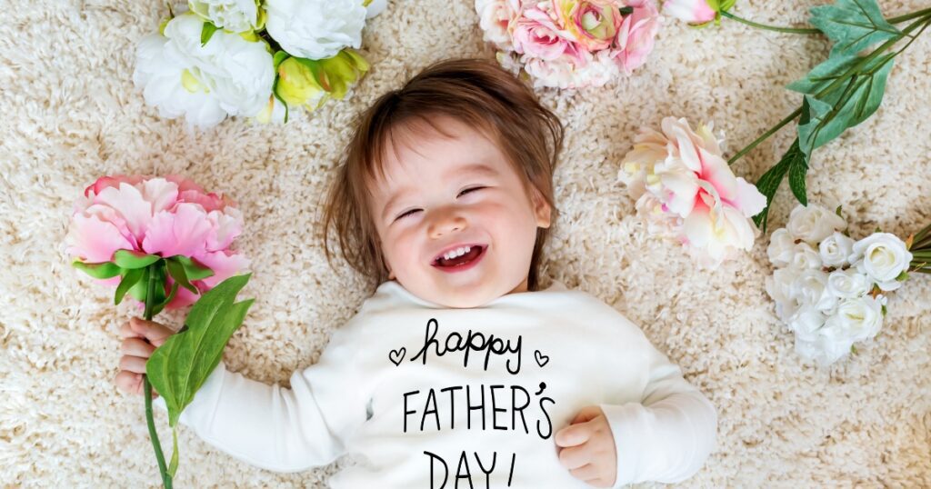 toddler fathers day gifts. Picture of a toddler laying down with flowers around them with a shirt that says happy father's day.