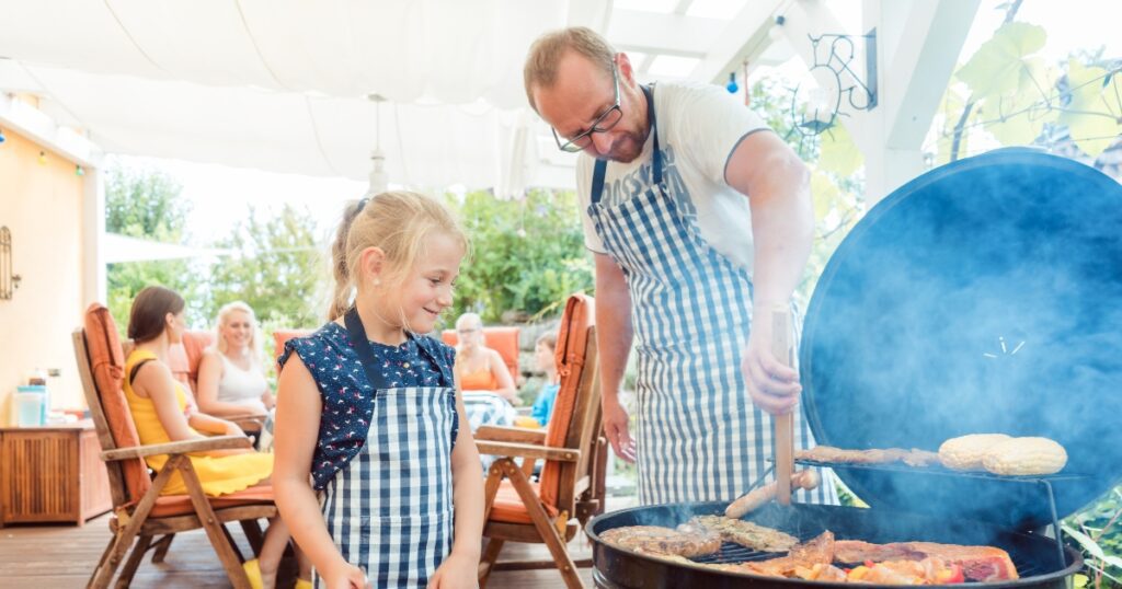 toddler fathers day gifts. Picture of a dad grilling with his daughter watching.