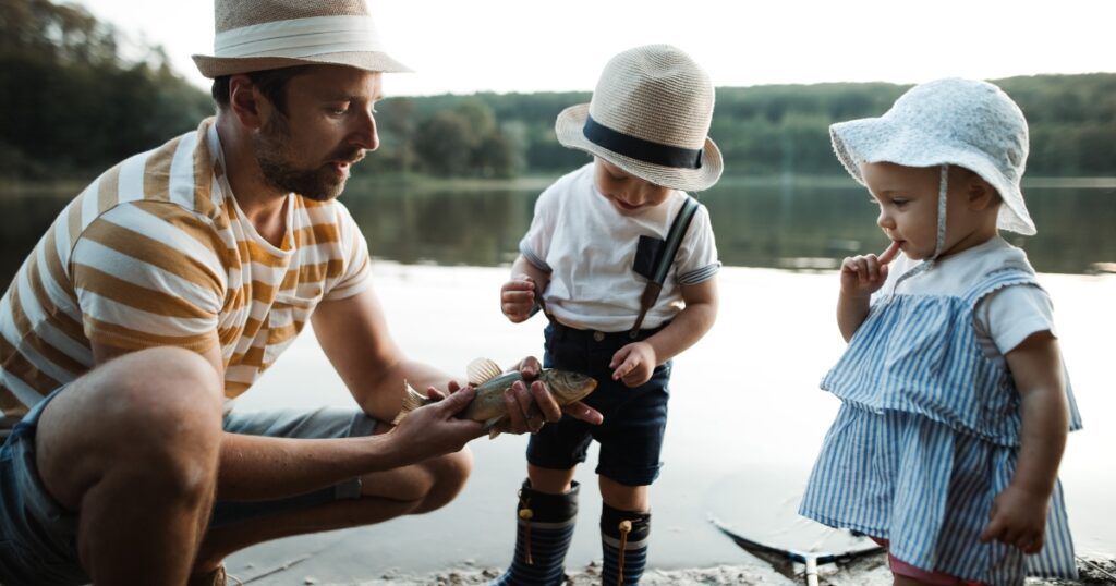toddler fathers day gifts. Picture of a father wtih two toddlers and the dad is teaching them how to fish.
