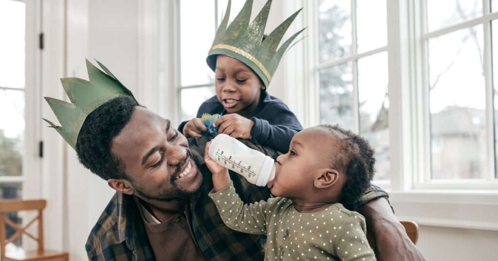 toddler fathers day gifts. Picture of a father wtih two small children playing and wearing paper crowns.